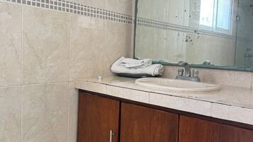A bathroom with a marble floor, a sink with a mirror above it, and wooden cabinets.
