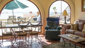 A furnished living room with a view of the sea, a dining area with chairs and a table, and a ceiling fan. - Wonderful 3-bedroom house in Las Gaviotas perfect for your getaway (Las Gaviotas)