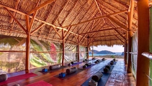 A yoga studio with wooden beams, mats, and blocks arranged for practice. - Eden Yoga & Wellness Resort (San Juan del Sur)
