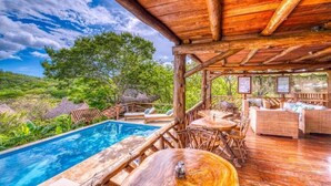 A wooden deck with a pool, lounge chairs, and a covered seating area. - Eden Yoga & Wellness Resort (San Juan del Sur)