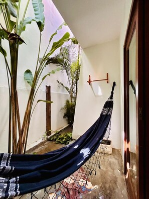 A hammock hanging in a corner, a white wall, and a door frame.