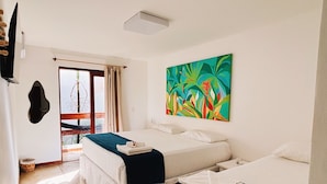 Habitación de hotel con dos camas, un ventanal grande, un cuadro colorido y vistas al exterior.