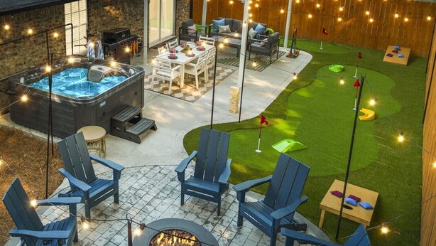 Ein Garten mit Whirlpool, Sitzgelegenheiten im Freien, einer Feuerstelle und einem kleinen Rasen mit Putting Green.