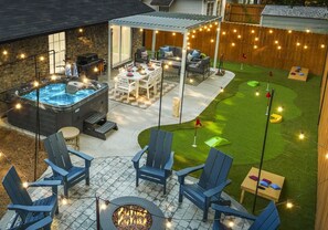 A backyard with a hot tub, outdoor seating, a fire pit, and a small lawn with a putting green. - Downtown/Tybee - HotTub+MiniGolf+Arcade+Karaoke (Savannah)