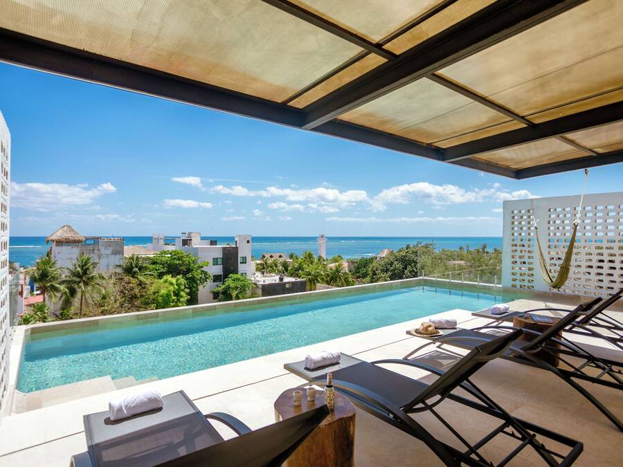 Zona de piscina con sillones de descanso, piscina y vista al océano.