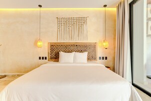 Una habitación de hotel moderna con una cama grande, un tapiz decorativo y dos lámparas de pared.