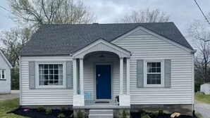 A single-story house with a front porch, a blue door, and a small front yard. - The Haven near the lake and Nash! 3bd/2ba (Hendersonville)