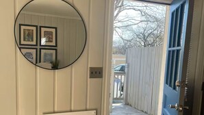 A hallway with a white radiator, a round mirror, and a blue door leading outside. - The Haven near the lake and Nash! 3bd/2ba (Hendersonville)