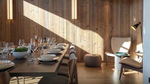 Un comedor moderno con pared de madera, luces colgantes y una mesa redonda dispuesta para una comida.