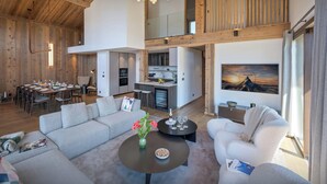 Un espacio habitable amplio con techo alto, vigas de madera, zona de comedor y cocina.