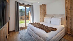 Un dormitorio con una cama grande, un armario de madera y un ventanal corredero que da a un balcón.