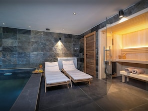 Un moderno spa con pared de piedra, puerta de madera y cabina de ducha de cristal.