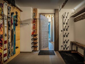Ein Flur mit Skiständern, einer Holzwand und einer Tür zu einem weiteren Raum.