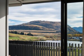A view of a mountainous landscape through a window with a wooden fence in the foreground. - Clubhouse 213 Golfside Free Parking AC (Jack's Point)