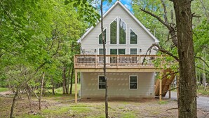 A two-story house with a balcony, surrounded by trees. - The Ultimate Social Stay - 6BRs, Hot Tub, Arcade, Fire Pit. SUMMER SAVINGS! (Albrightsville)