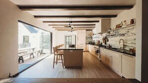 Une cuisine moderne dotée d’un îlot central, d’un plancher en bois et offrant une vue sur l’extérieur.