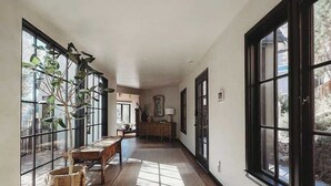 Un couloir doté de grandes fenêtres, d’un plancher en bois et d’une plante.