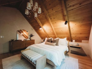 A bedroom with a wooden ceiling, a bed with white bedding, a nightstand, and a dresser. - Lakeside Willow (on lake trail, steps from water) (Lake Arrowhead)
