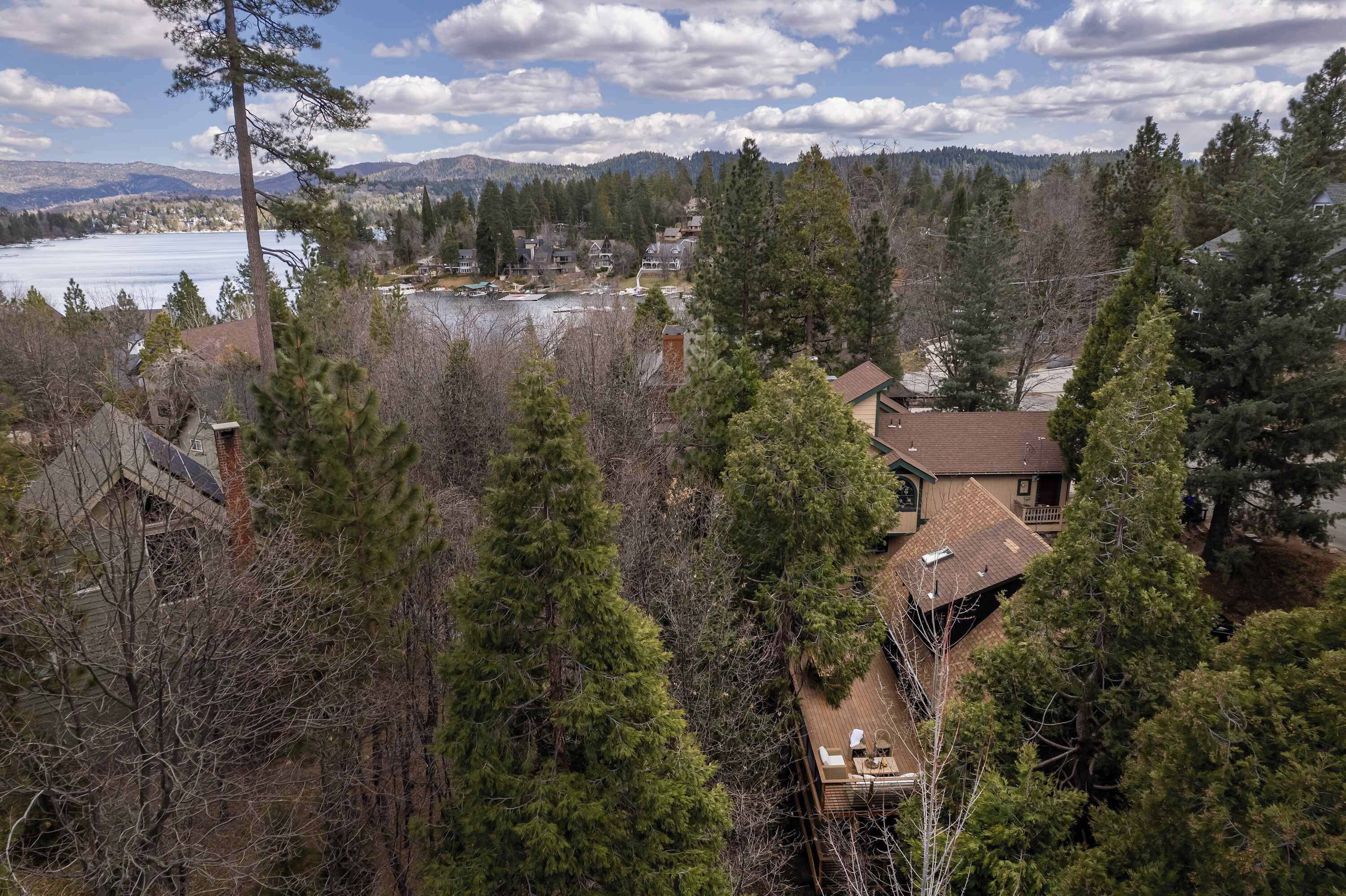 A residential area with a house featuring a deck and a view of a lake and mountains.