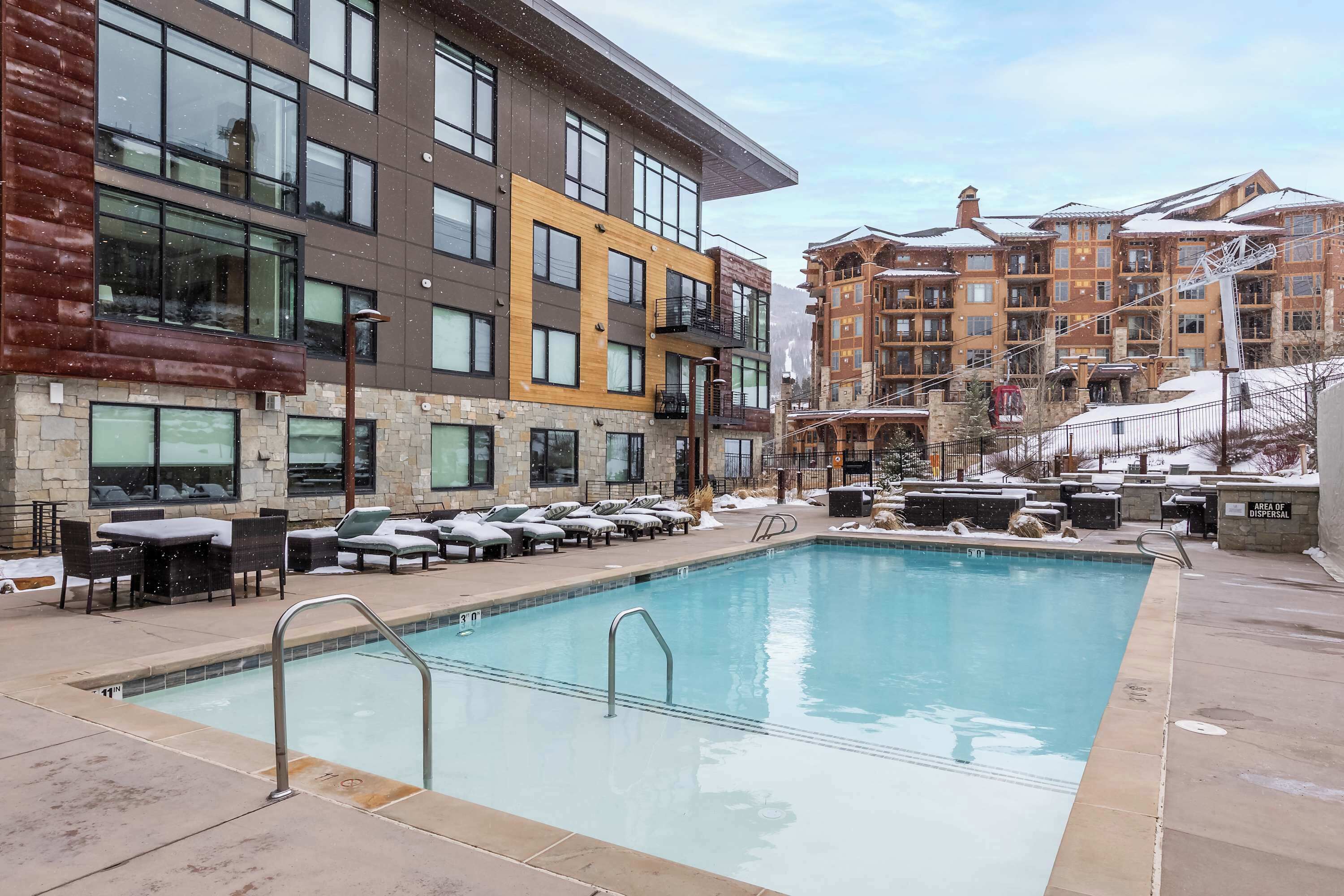 Ett hotell med en swimmingpool, utomhusplats och utsikt över snötäckta byggnader.