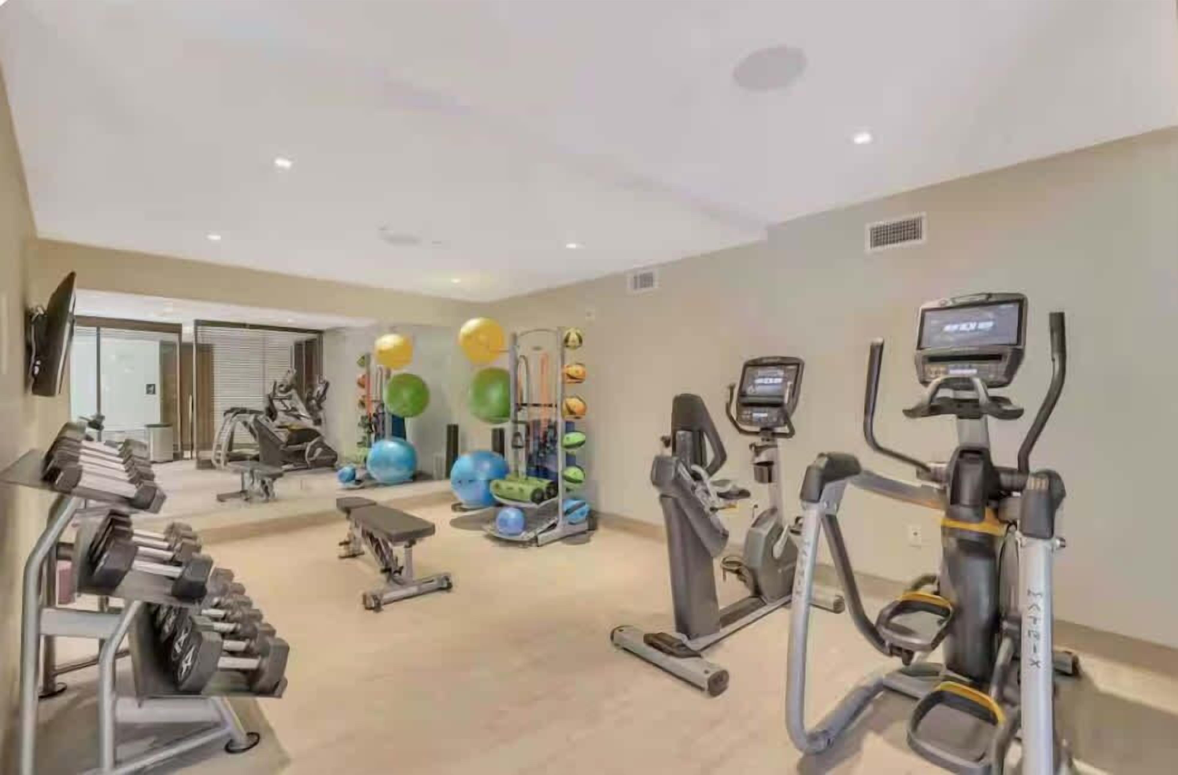 Une salle de sport équipée de tapis de course, de vélos elliptiques et de poids libres.