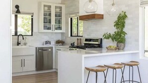 A modern kitchen with white cabinetry, a central island with stools, a dishwasher, and a stove. - West Shore Waterview, (walk to lake & North Bay!) (Lake Arrowhead)