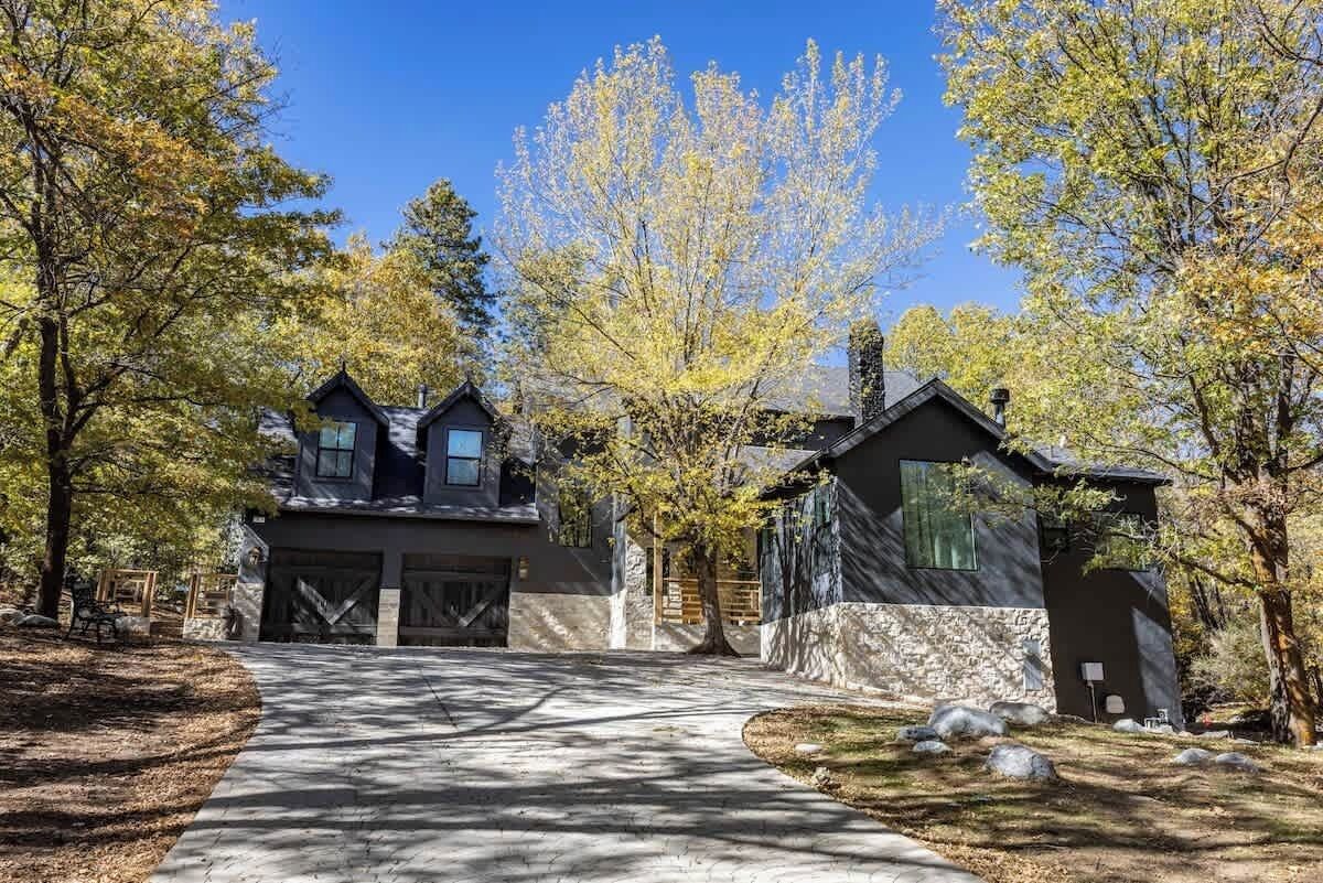 Una casa moderna de dos pisos con garaje, rodeada de árboles y un sendero de piedra.