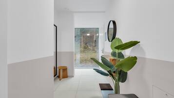Ein modernes Interieur mit einem großen Fenster, einer Pflanze und einer Bank.