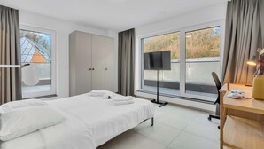 Een hotelkamer met een bed, een bureau, een flatscreen-televisie en grote ramen.
