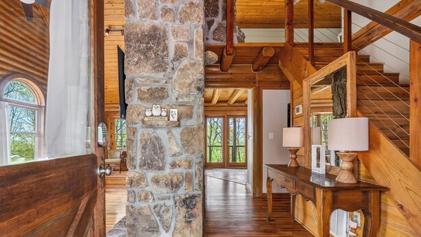 Un intérieur en bois avec un pilier en pierre, un escalier et une vue sur l’extérieur.