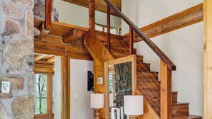 Un escalier en bois avec un mur en pierre, un bureau en bois avec des lampes et un ventilateur de plafond.