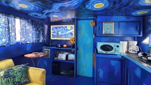 A room with a blue color scheme, a bed, a small table, a sofa, and a television. - Sleep in a Van Gogh painting! A floating tribute to the art of Vincent. (League City)