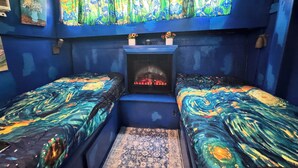 A room with two beds, a fireplace, and a patterned curtain. - Sleep in a Van Gogh painting! A floating tribute to the art of Vincent. (League City)