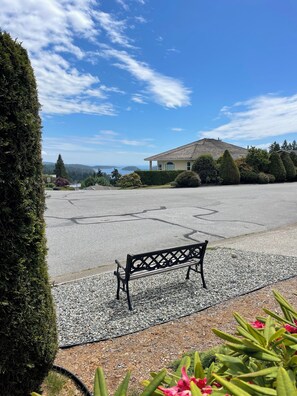 A bench in a gravel area with a house in the background. - Cozy Oceanmount 1BR Suite with Sofa Bed – Ideal Escape (Gibsons)