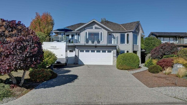 A two-story house with a garage, a covered driveway, and a large RV parked in front. - Cozy Oceanmount 1BR Suite with Sofa Bed – Ideal Escape (Gibsons)
