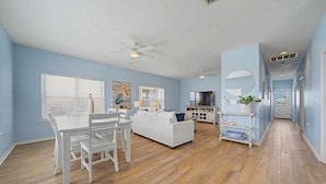 A spacious living area with a dining table, white sofa, and a kitchen in the background. - New listing! Private pool, steps to the beach (Gulf Shores)