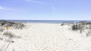 A sandy beach with a clear sky, a sign on the left, and a fence on the right. - New listing! Private pool, steps to the beach (Gulf Shores)