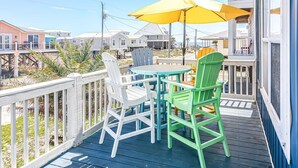 A deck with a table and chairs, a yellow umbrella, and a view of beach houses. - New listing! Private pool, steps to the beach (Gulf Shores)