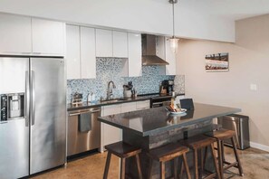 Kitchen with island seating and steel fridge - Pipes Canyon Retreat · 2 Homes, 10 Acres, Hot Tubs (Yucca Valley)