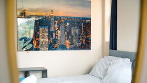 Et hotelværelse med en seng, et natbord, et bybillede og udsigt over værelset.