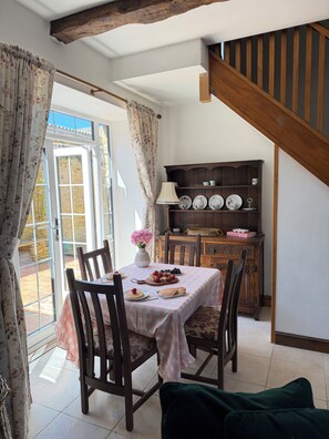 A dining area with a table set for four, a wooden cabinet with dishes, and a staircase.