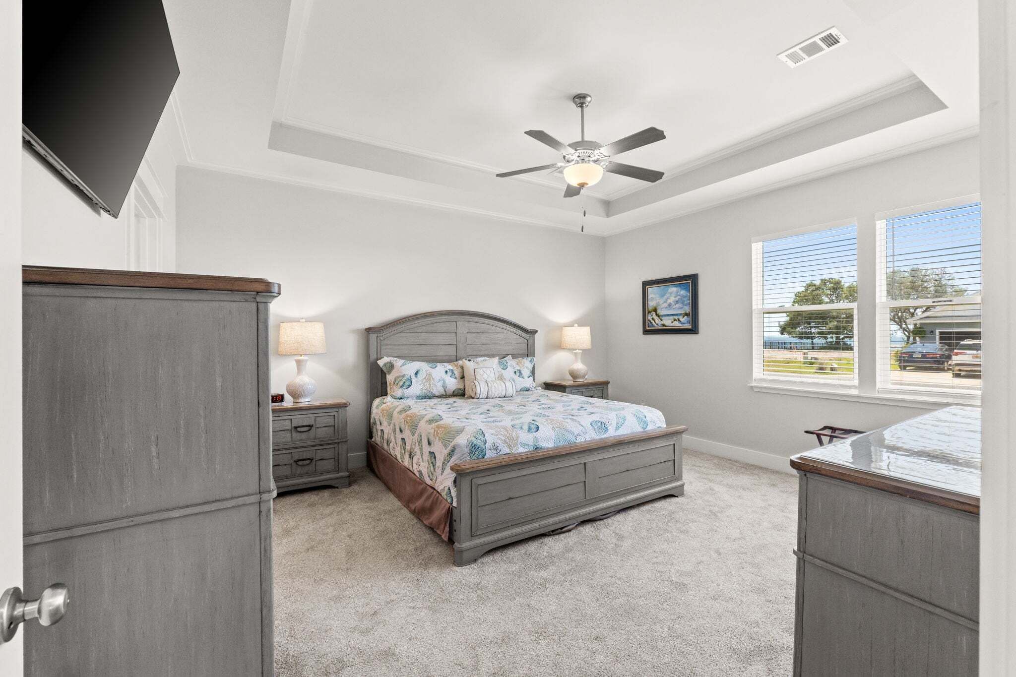 A bedroom with a bed, nightstands, a ceiling fan, a window, and a door.
