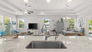 A modern kitchen with a large island, built-in appliances, and a dining area with a view. - Fall Deals + Snowbird Rates | Coastal Stay With Bay Views (Eastpoint)