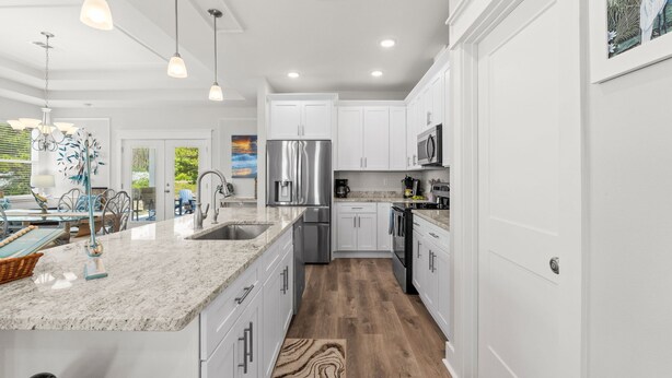 A modern kitchen with white cabinets, stainless steel appliances, and pendant lighting. - Fall Deals + Snowbird Rates | Coastal Stay With Bay Views (Eastpoint)