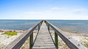 A wooden pier leading to a beach with clear water and a clear sky. - Fall Deals + Snowbird Rates | Coastal Stay With Bay Views (Eastpoint)