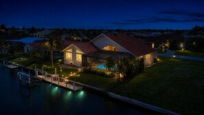 A residential property with a swimming pool, dock, and well-lit outdoor areas. - Punta Gorda Isles Vacation Home with Private Pool on Canal with a Boat Dock (Punta Gorda)