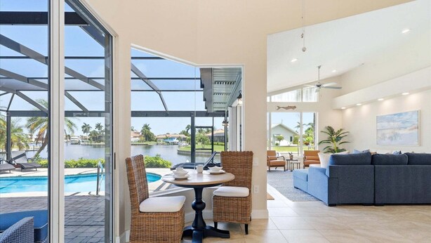 A modern living room with a view of a swimming pool and a patio area. - Punta Gorda Isles Vacation Home with Private Pool on Canal with a Boat Dock (Punta Gorda)