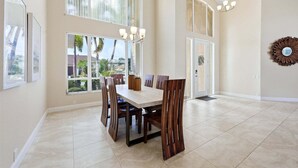 A spacious dining area with a large table, chairs, and a view of palm trees outside. - Punta Gorda Isles Vacation Home with Private Pool on Canal with a Boat Dock (Punta Gorda)