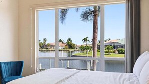 A hotel room with a large window, a bed, and a chair. - Punta Gorda Isles Vacation Home with Private Pool on Canal with a Boat Dock (Punta Gorda)