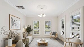 A living room with a sofa, armchairs, a coffee table, and a ceiling fan.